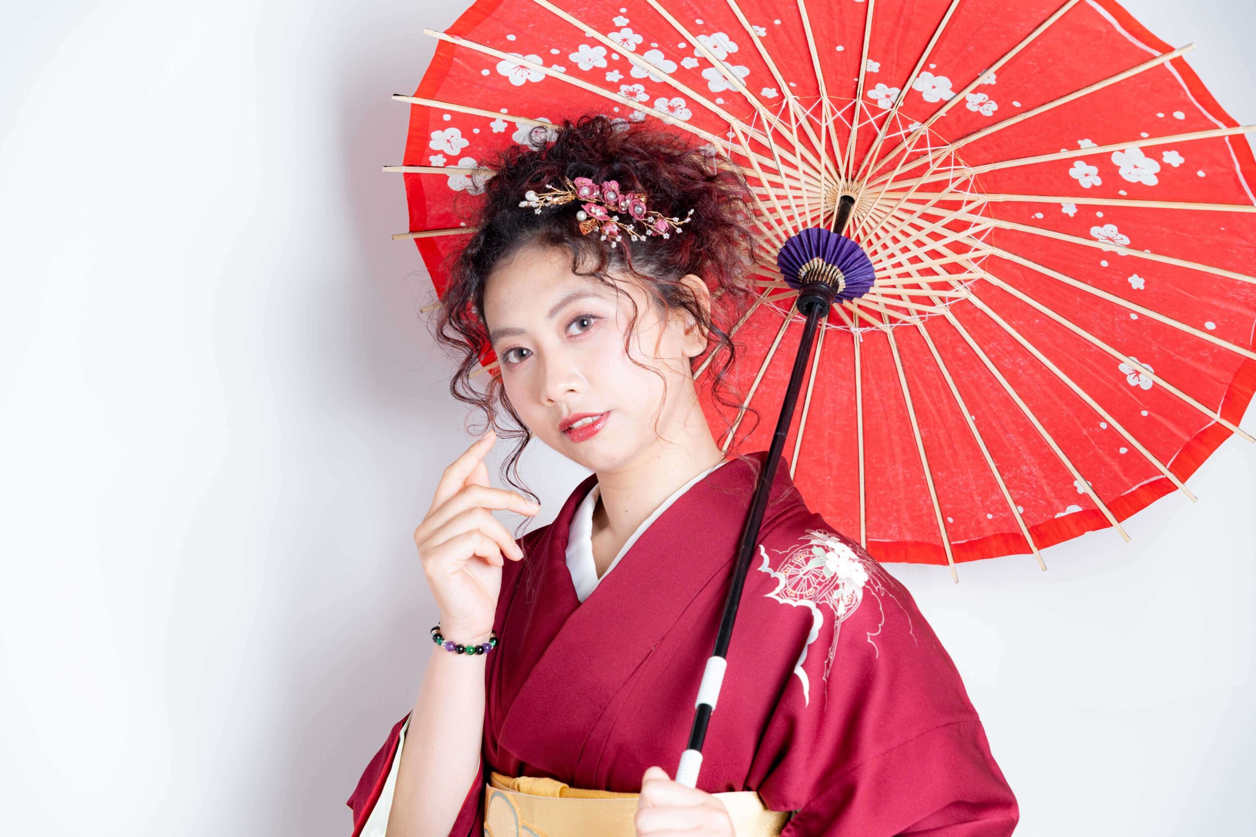 Woman wearing red kimono holding traditional Japanese umbrella during studio photoshoot in Tokyo