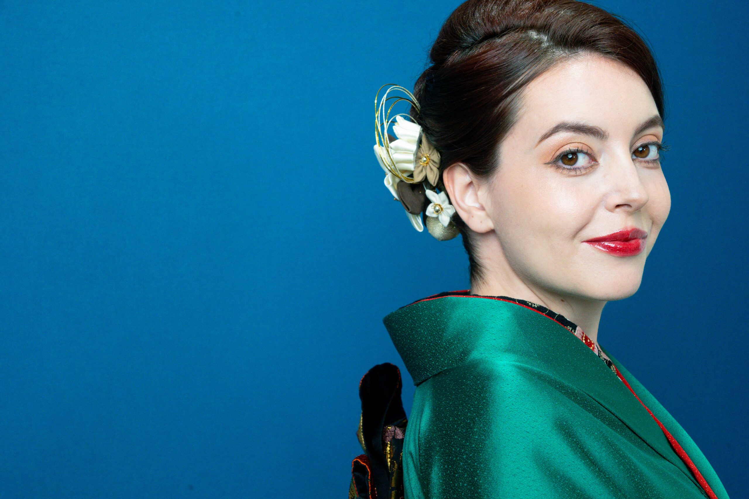Completed kimono hair and makeup look — green kimono, red lips, blue backdrop