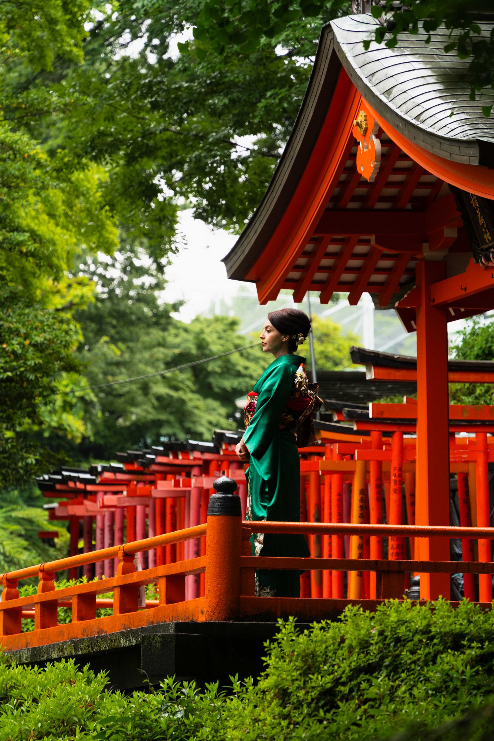 She stands at Nezu Shrine with red torii gates and a traditional bridge