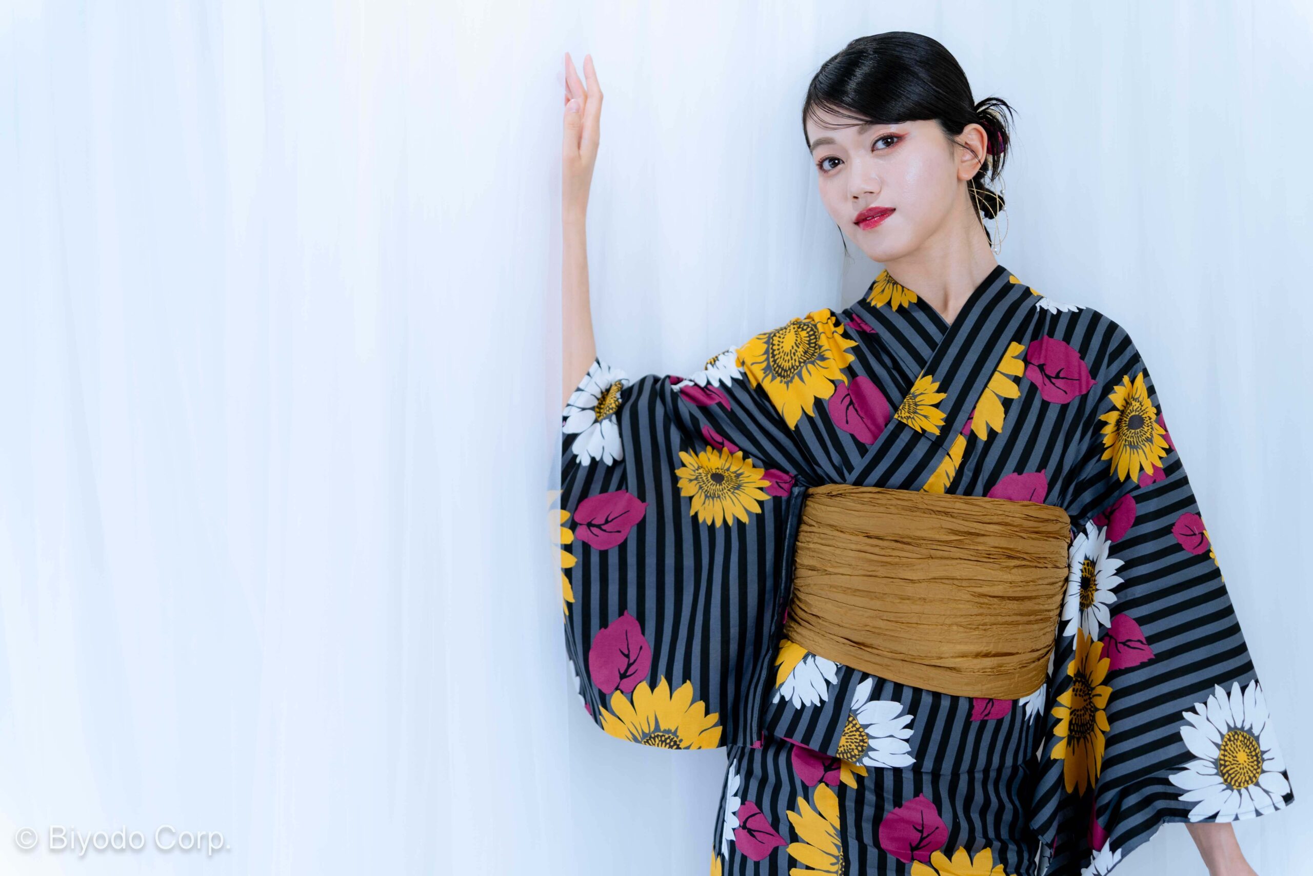 Woman wearing striped sunflower-pattern yukata during studio photoshoot in Tokyo