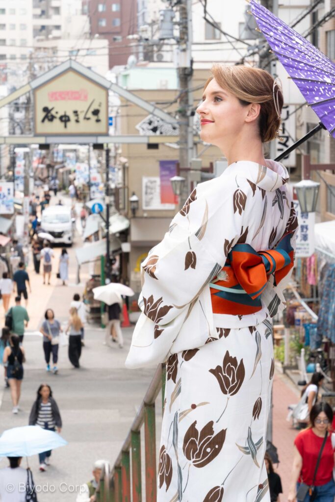Guest in kimono with a paper umbrella at Yanaka Ginza shopping street, Tokyo